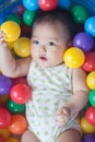 Cute baby lying in colorful toy balls and playing happily