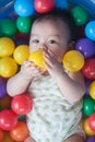 Cute baby lying in colorful toy balls and playing happily