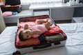 Cute baby lying in an open suitcase containing clothes