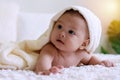 Cute baby lying under white blanket looking at something. Innocence baby crawling on white bed with towel on his head at Royalty Free Stock Photo