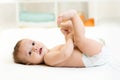 Cute baby lying on white sheet and holding his Royalty Free Stock Photo