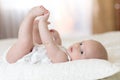Cute baby lying on white sheet and holding his legs Royalty Free Stock Photo