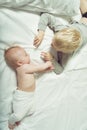 Cute baby and older brother interact while lying on the bed. Top view Royalty Free Stock Photo