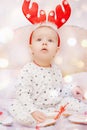 Cute baby in pajamas and deer horns on christmas background Royalty Free Stock Photo