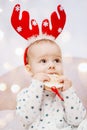 Cute baby in pajamas and deer horns on christmas background Royalty Free Stock Photo