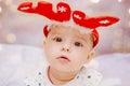 Cute baby in pajamas and deer horns on christmas background Royalty Free Stock Photo