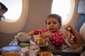 Cute baby passenger eats in aircraft special meal. infant young traveler Royalty Free Stock Photo