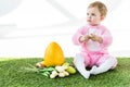 Baby in pink fluffy costume sitting near yellow ostrich egg, colorful chicken eggs and tulips  on white Royalty Free Stock Photo