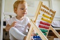 Cute baby playing colorful abacus with wooden beads kids toy enjoying self educational game Royalty Free Stock Photo