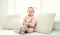 Cute baby playing with teddy toy home in white room near wind