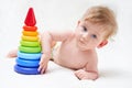 Cute baby plays with a multi-colored toy pyramid on a light background Royalty Free Stock Photo