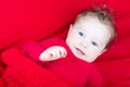 Cute baby in red sweater under red blanket Royalty Free Stock Photo