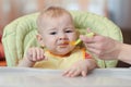 Cute baby boy refusing to eat food from spoon with face dirty of vegetable puree. Royalty Free Stock Photo