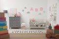 Cute baby room interior with crib and chest of drawers near wall Royalty Free Stock Photo