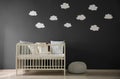 Cute baby room interior with modern crib near decorative clouds on wall Royalty Free Stock Photo