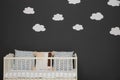 Cute baby room interior with modern crib near decorative clouds on wall Royalty Free Stock Photo