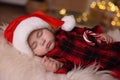 Cute baby in Santa hat with candy cane sleeping on soft faux fur indoors. Christmas season Royalty Free Stock Photo