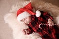 Cute baby in Santa hat with candy cane sleeping on soft faux fur, top view. Christmas season Royalty Free Stock Photo