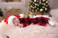 Cute baby in Santa hat sleeping on soft faux fur indoors. Christmas season