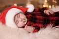 Cute baby in Santa hat sleeping on soft faux fur indoors. Christmas season Royalty Free Stock Photo