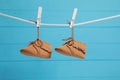 Cute baby shoes drying on washing line against light blue wooden wall Royalty Free Stock Photo