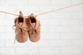 Cute baby shoes drying on washing line against white brick wall. Space for text Royalty Free Stock Photo