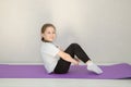 cute baby sits on a gymnastic mat with her knees bent and her feet stretched out, the child smiles Royalty Free Stock Photo