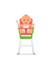 Cute baby sits on a high chair and holds a spoon. Baby healthy feeding concept.