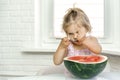 Little girl eating half a watermelon with a spoon