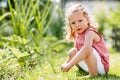 A cute baby is sitting on the grass in the park or in the garden