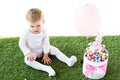 Baby sitting on green grass near box with colorful quail eggs, decorative rabbit and air balloon isolated on white Royalty Free Stock Photo