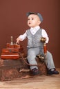 Cute baby sitting on a suitcase, holding a vintage phone