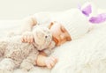 Cute baby sleeping with teddy bear toy on white soft bed Royalty Free Stock Photo