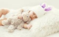 Cute baby sleeping with teddy bear toy on white soft bed home Royalty Free Stock Photo