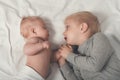 Cute baby and smiling older brother are lying on the bed. Play and interact. Top view Royalty Free Stock Photo