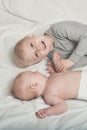 Cute baby and smiling older brother are lying on the bed. Play and interact. Top view Royalty Free Stock Photo