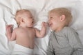 Cute baby and smiling older brother are lying on the bed. Play and interact. Top view Royalty Free Stock Photo