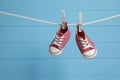 Cute baby sneakers drying on washing line against light blue wooden wall. Space for text Royalty Free Stock Photo