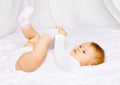 Cute baby in socks lying on the bed and holding legs Royalty Free Stock Photo
