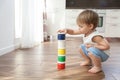 A cute baby stands next to the paints in the cans.