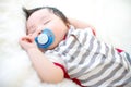 Cute baby is sucking pacifier and sleeping on a soft white carpet. Lovely baby lie down on a soft white carpet. Royalty Free Stock Photo