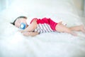 Cute baby is sucking pacifier and sleeping on a soft white carpet. Lovely baby lie down on a soft white carpet. image for backgrou Royalty Free Stock Photo