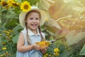 Cute baby on a sunflower field on a sunny day. A beautiful little girl in a straw hat cheerfully holds a glass bottle Royalty Free Stock Photo