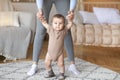 Cute baby taking first steps with mother help, home interior Royalty Free Stock Photo