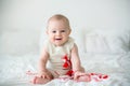 Cute baby toddler boy, playing with white and red bracelets Royalty Free Stock Photo