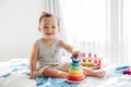 Cute baby toddler playing with learning toy pyramid stacking blocks at home. Early age Montessori education. Kids hand brain fun Royalty Free Stock Photo