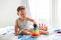 Cute baby toddler playing with learning toy pyramid stacking blocks at home. Early age Montessori education. Kids hand brain fun Royalty Free Stock Photo