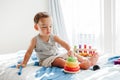 Cute baby toddler playing with learning toy pyramid stacking blocks at home. Early age Montessori education. Kids hand brain fun