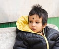 Cute baby wearing winter clothing sitting on a park bench outdoors Royalty Free Stock Photo