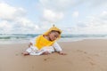 Cute baby wearing a yellow duck cartoon bathrobe sitting and playing on the beach near the sea Royalty Free Stock Photo